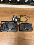 Two Panasonic GX85 Camera Bodies, One With Cage + Extra Batteries. Fixed Price $800.00.